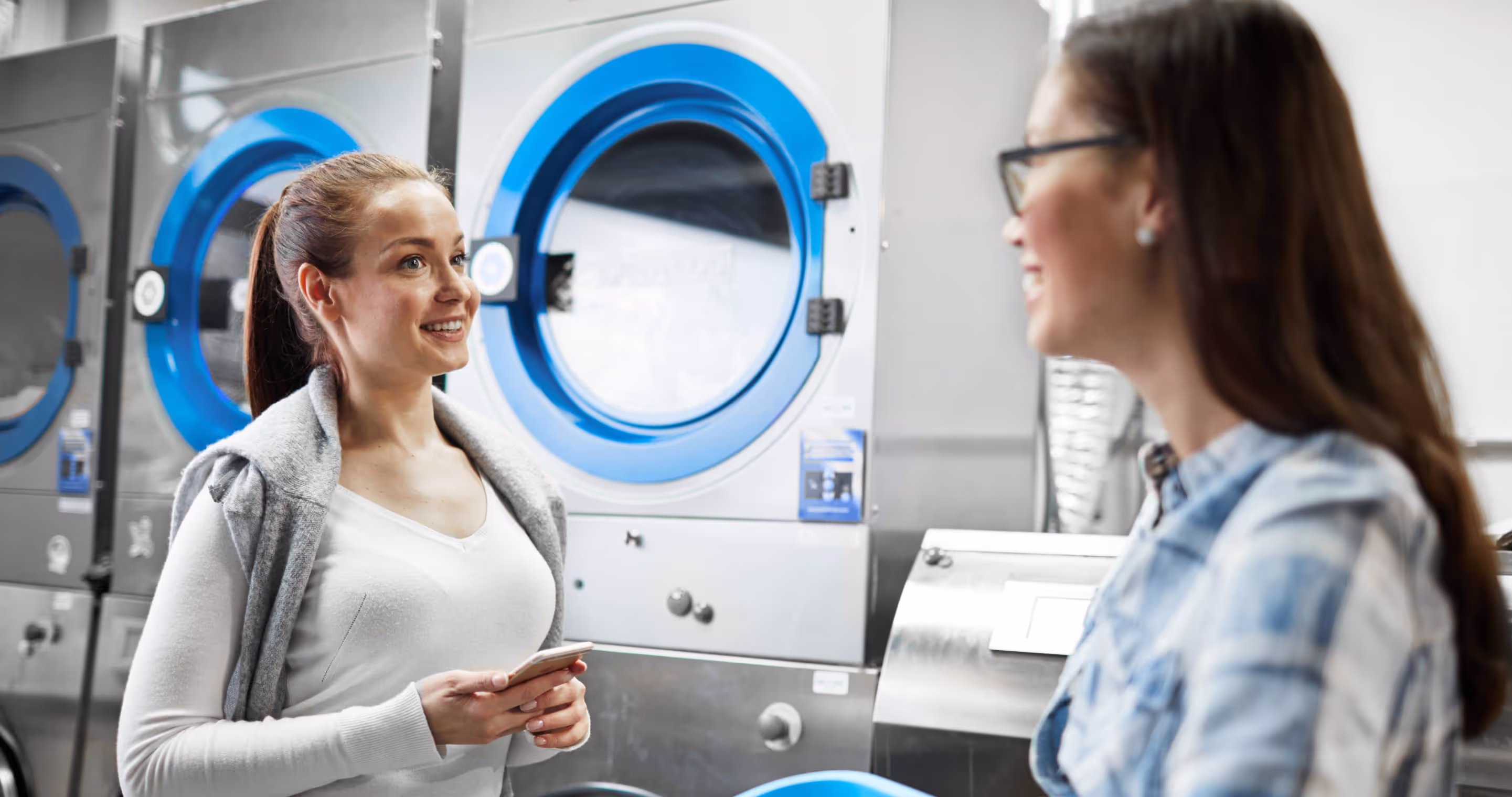 Two people chatting by the washing machines