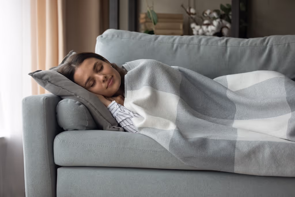 Woman napping on a sofa with clean cushions and throws